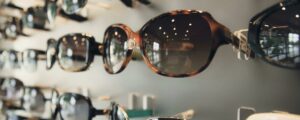 A variety of fashionable sunglasses on display in an optical store with soft lighting.