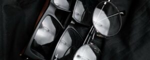 Close-up of various stylish eyeglasses on black fabric, highlighting modern eyewear design.