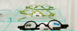 Stylish green and black eyeglasses on glass shelves, showcasing modern eyewear design.