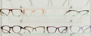 Stylish rims with lenses for vision arranged on glass shelves in ophthalmology salon